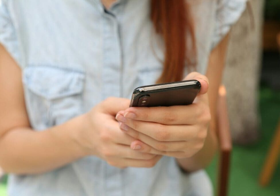 A woman holding her cell phone in both hands.